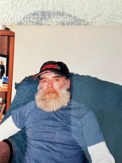 A man with a beard and hat is sitting on a couch.