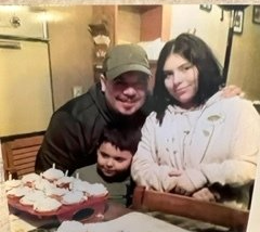 A family is posing for a picture in a kitchen with cupcakes on the table.