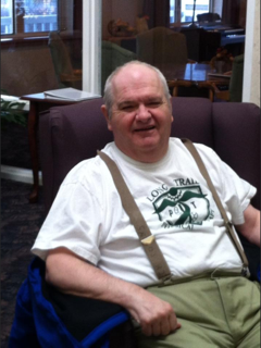 A man wearing suspenders is sitting in a chair