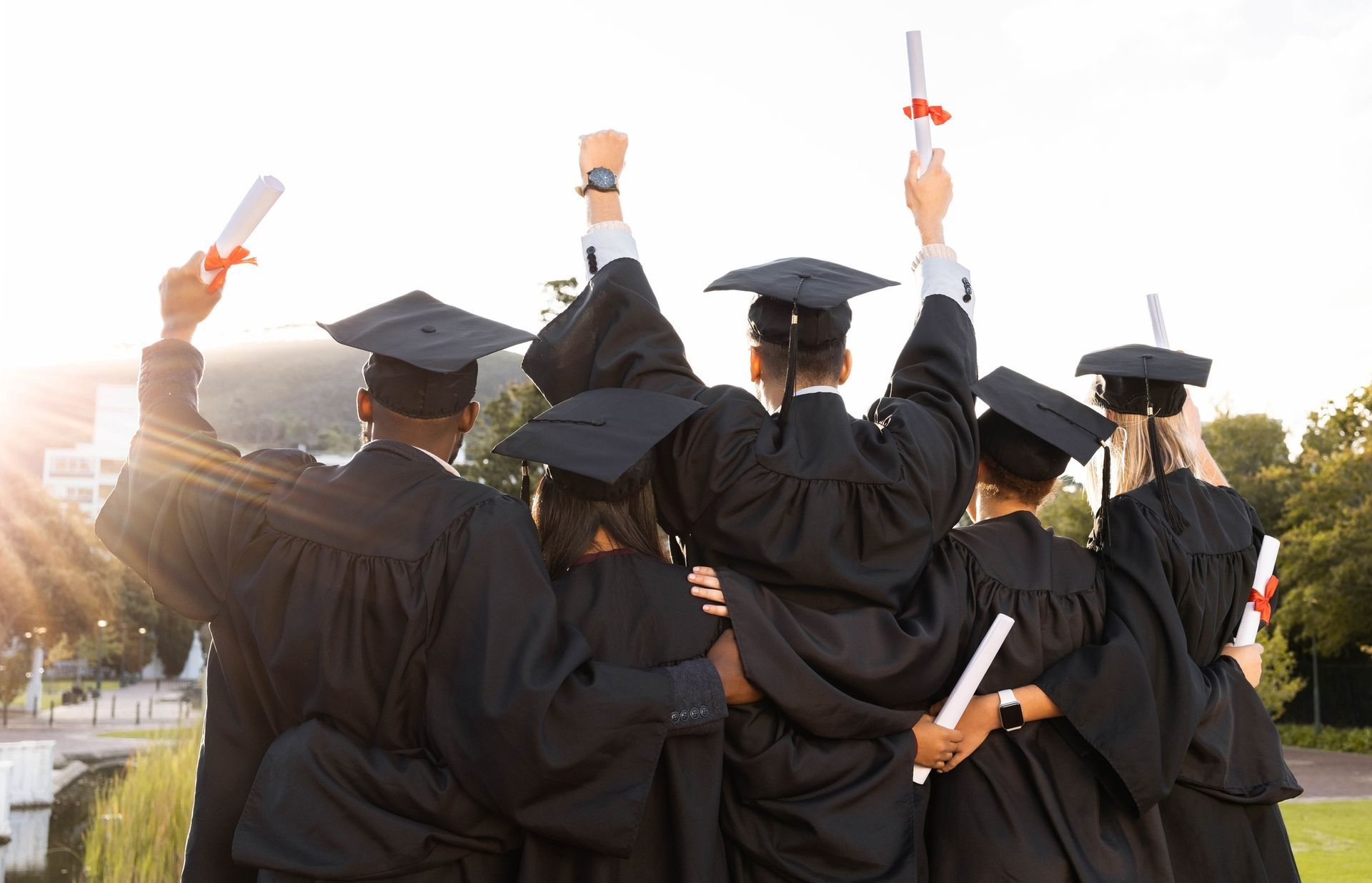 A group of graduates are standing next to each other holding their diplomas in the air.