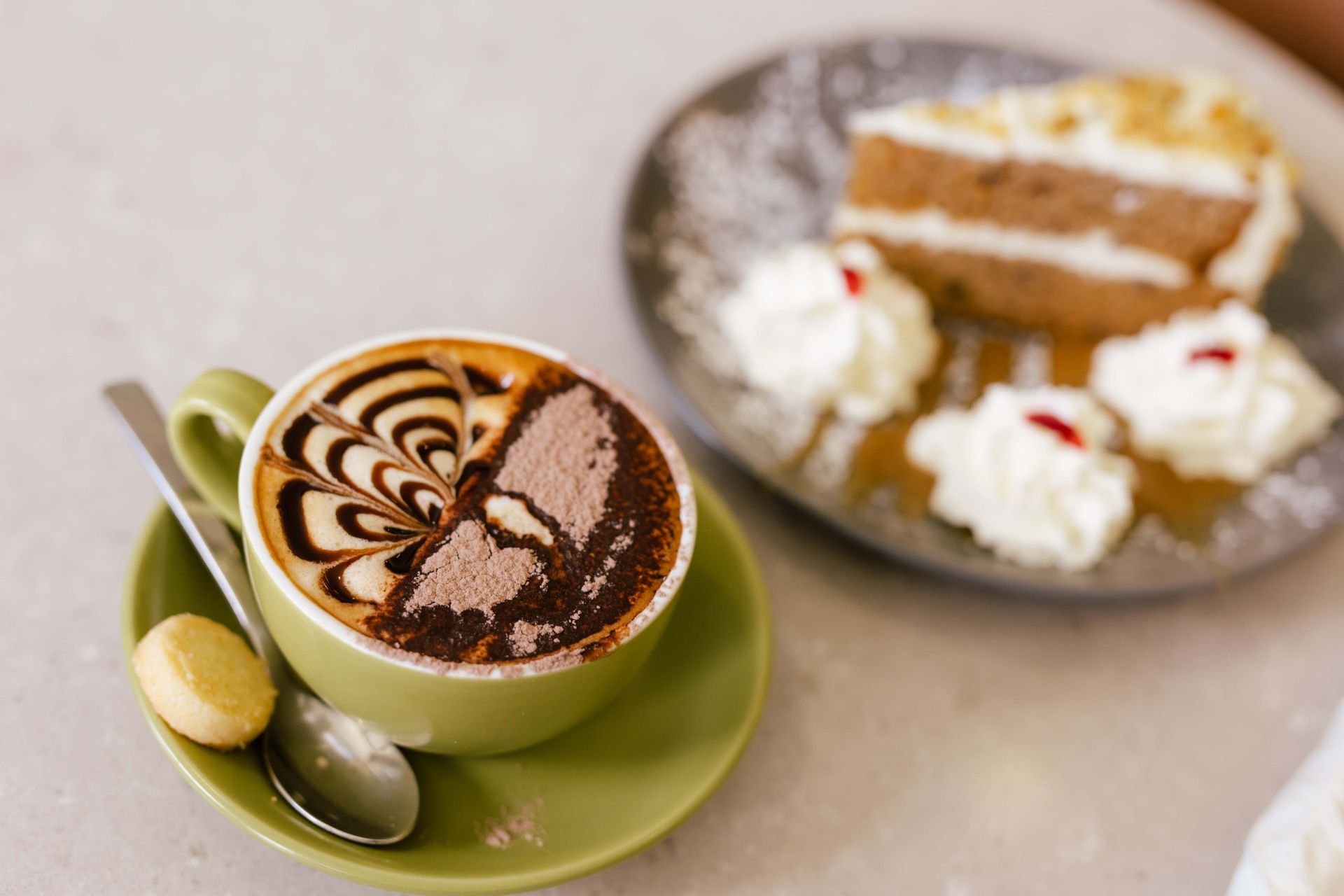 A cappuccino next to a plate of cake