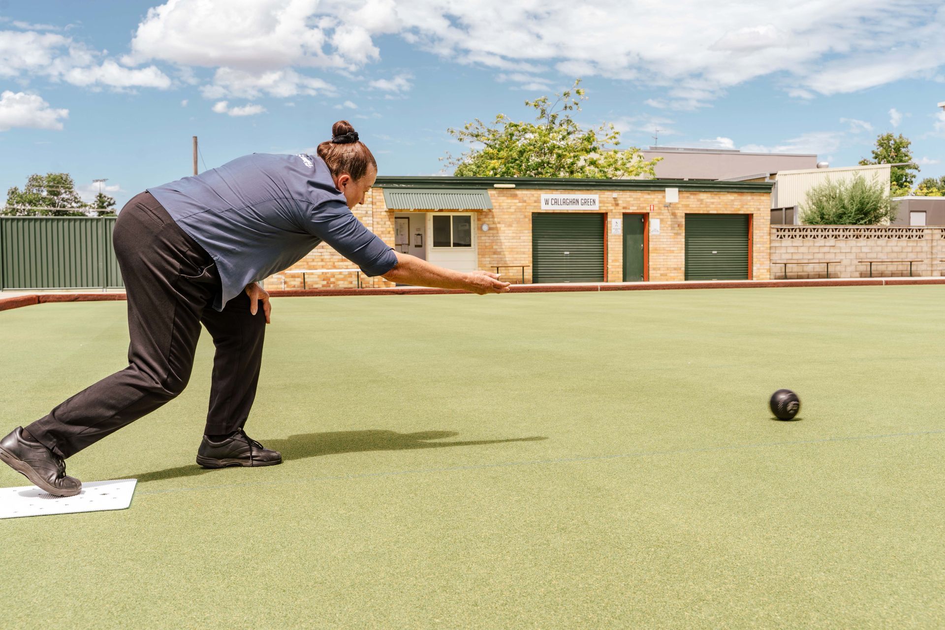 A woman is playing a game of bowling on a green field
