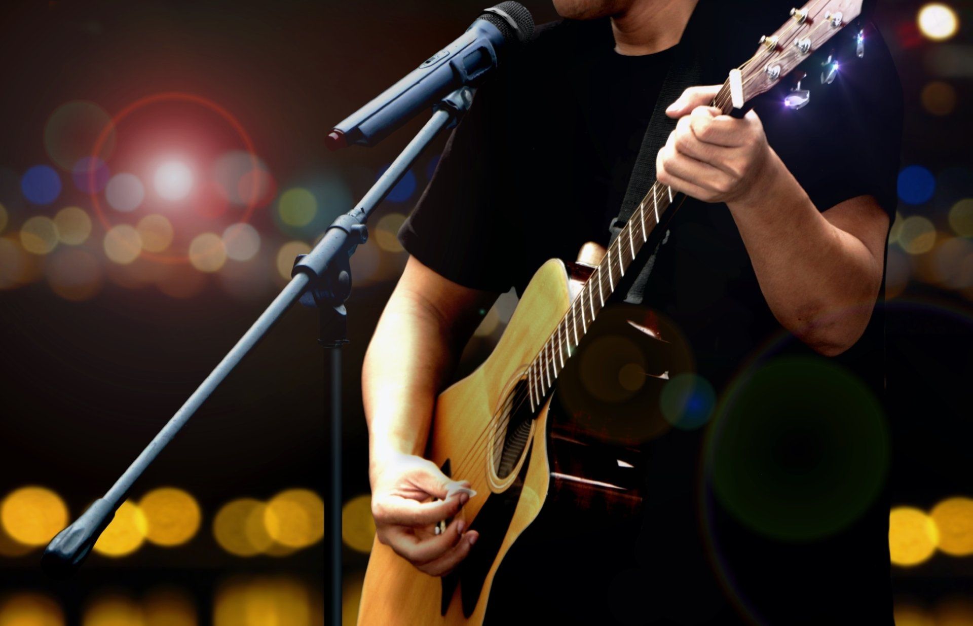 A man singing into a microphone while playing an acoustic guitar