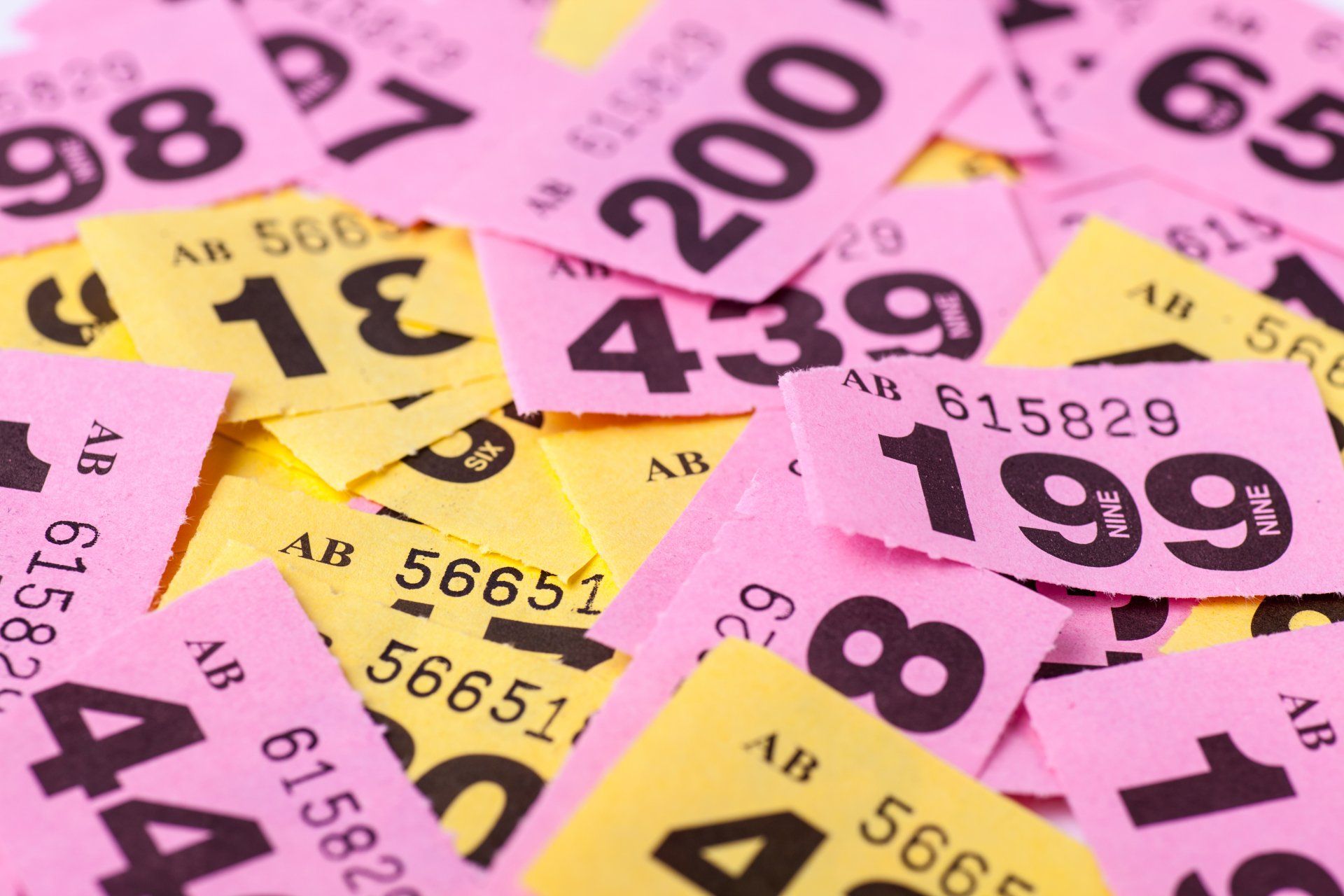 A pile of pink and yellow tickets with numbers on them