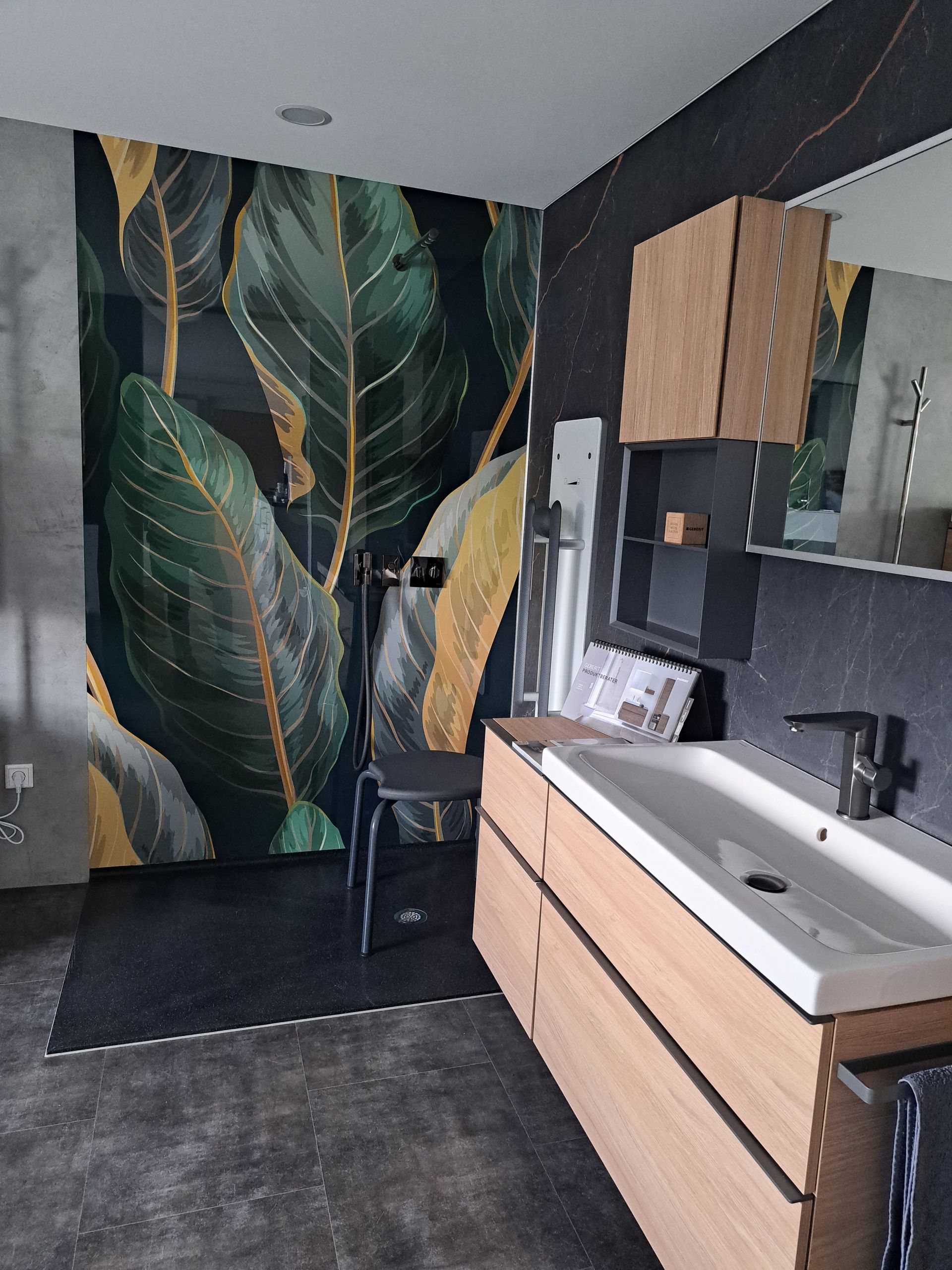 Ein Badezimmer mit Waschbecken, Spiegel und einer großen Blättertapete an der Wand.