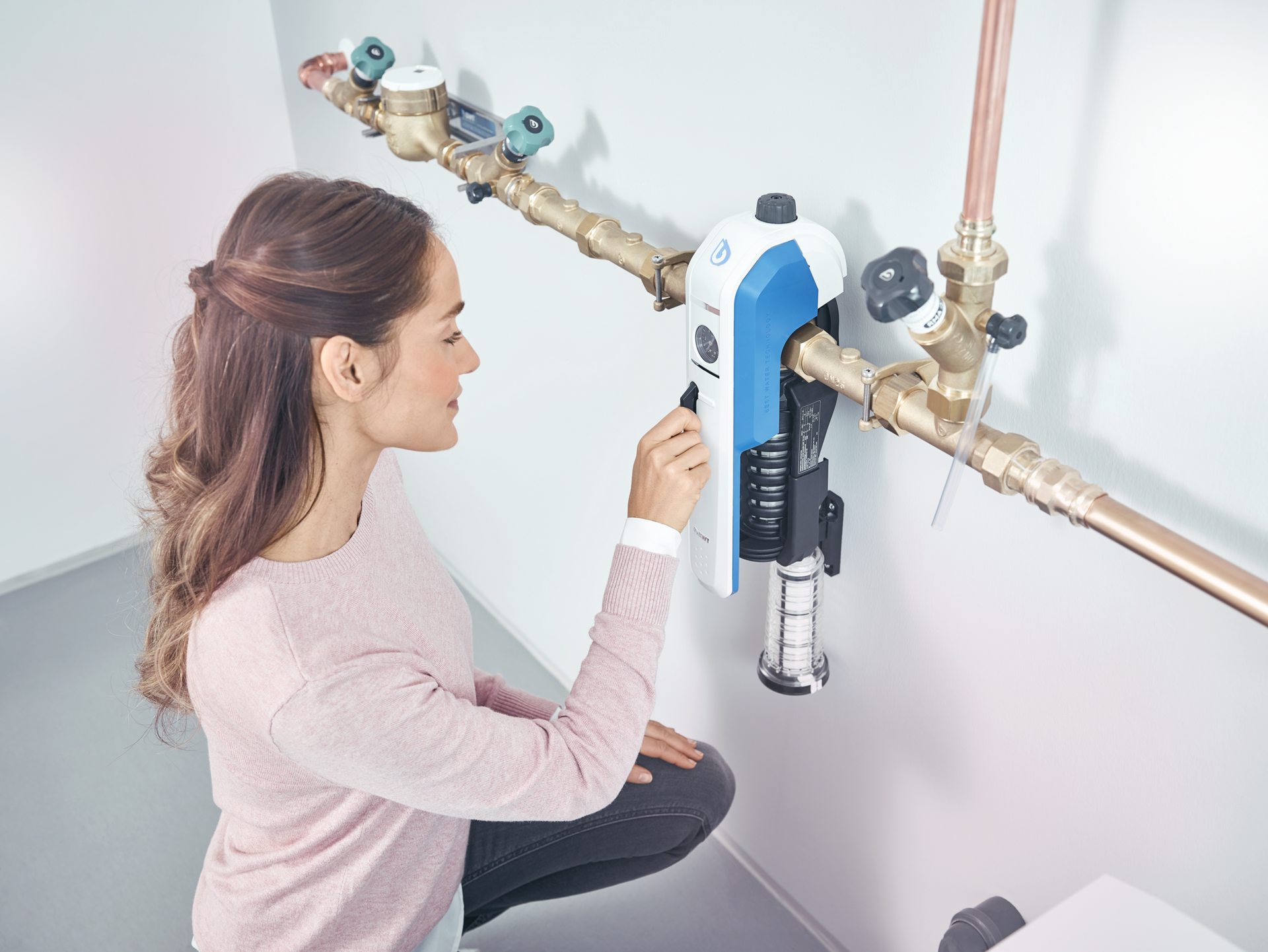 Eine Frau installiert einen Wasserfilter an einer Wand.