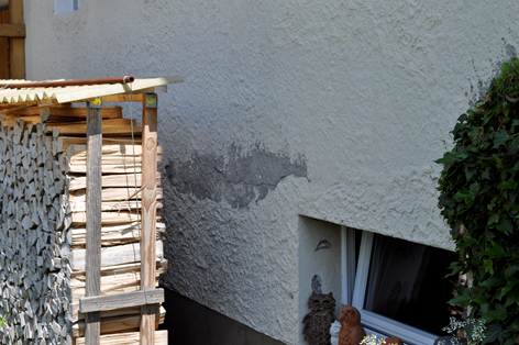Ein weißes Gebäude mit einem Fenster und einer Holzkonstruktion davor