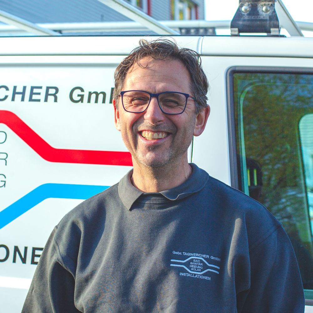 Ein Mann mit Brille lächelt vor einem weißen Lieferwagen mit der Aufschrift „Cher GML“