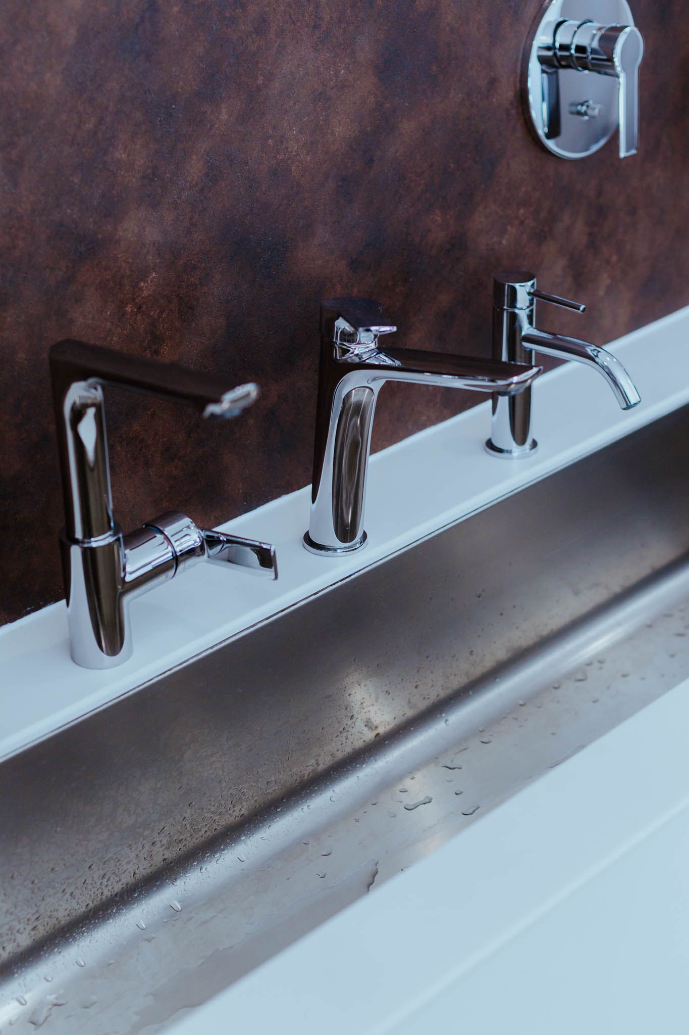 Eine Edelstahlspüle mit drei Wasserhähnen darauf
