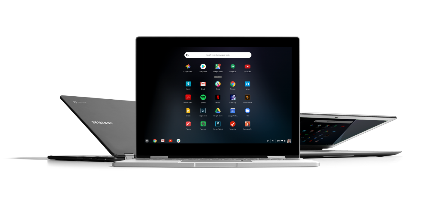 three laptops are sitting next to each other on a white surface .