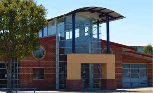 a brick building with a blue roof and a tree in front of it