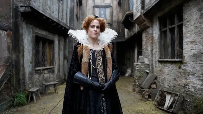 A seductive woman in a fifteenth-century dress is standing outside England.