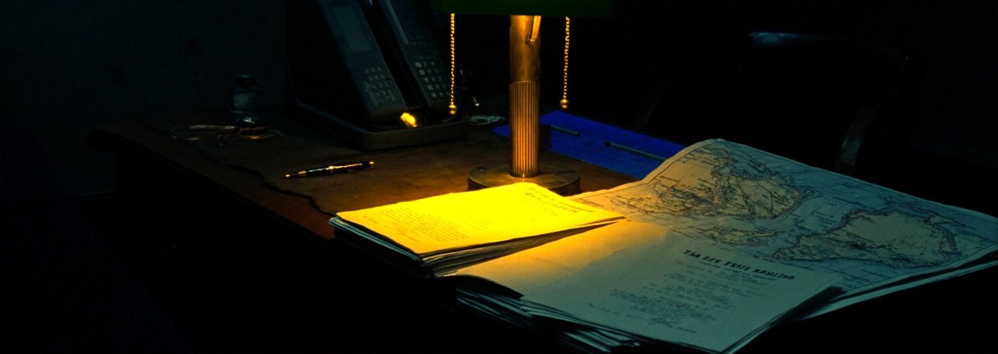 A desk lamp over film distribution contracts and a world map marked up by territory