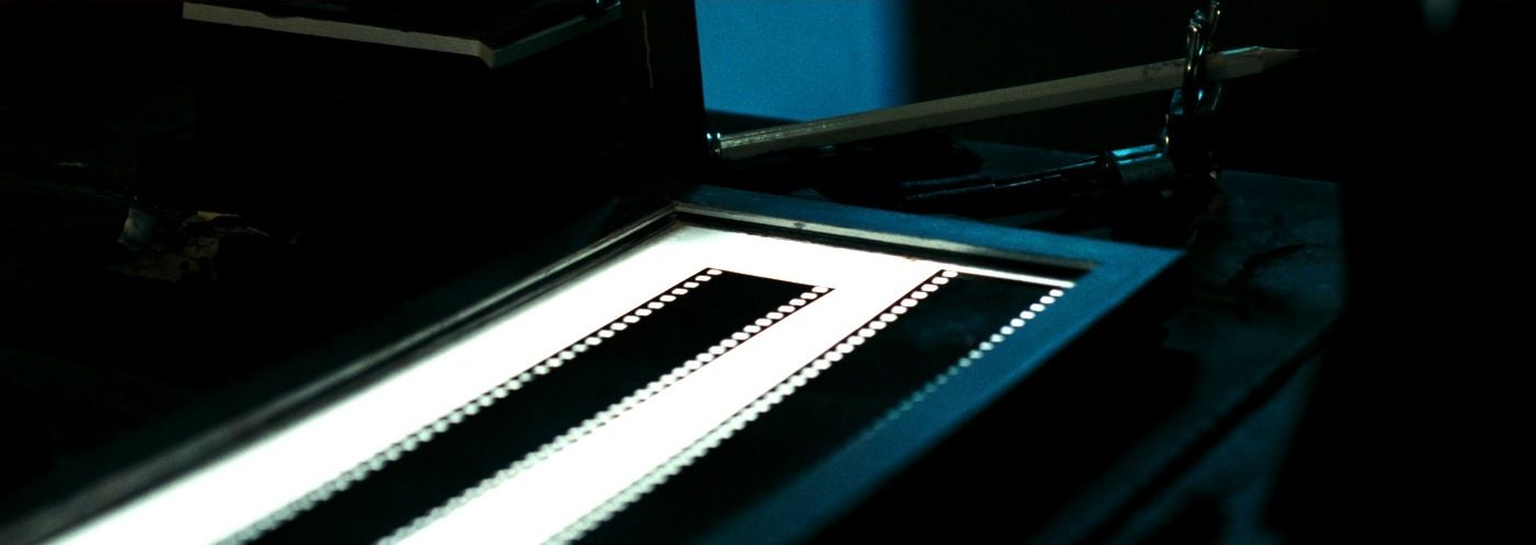 Two strips of 35mm film running side by side across a glowing lightbox on an editing bench