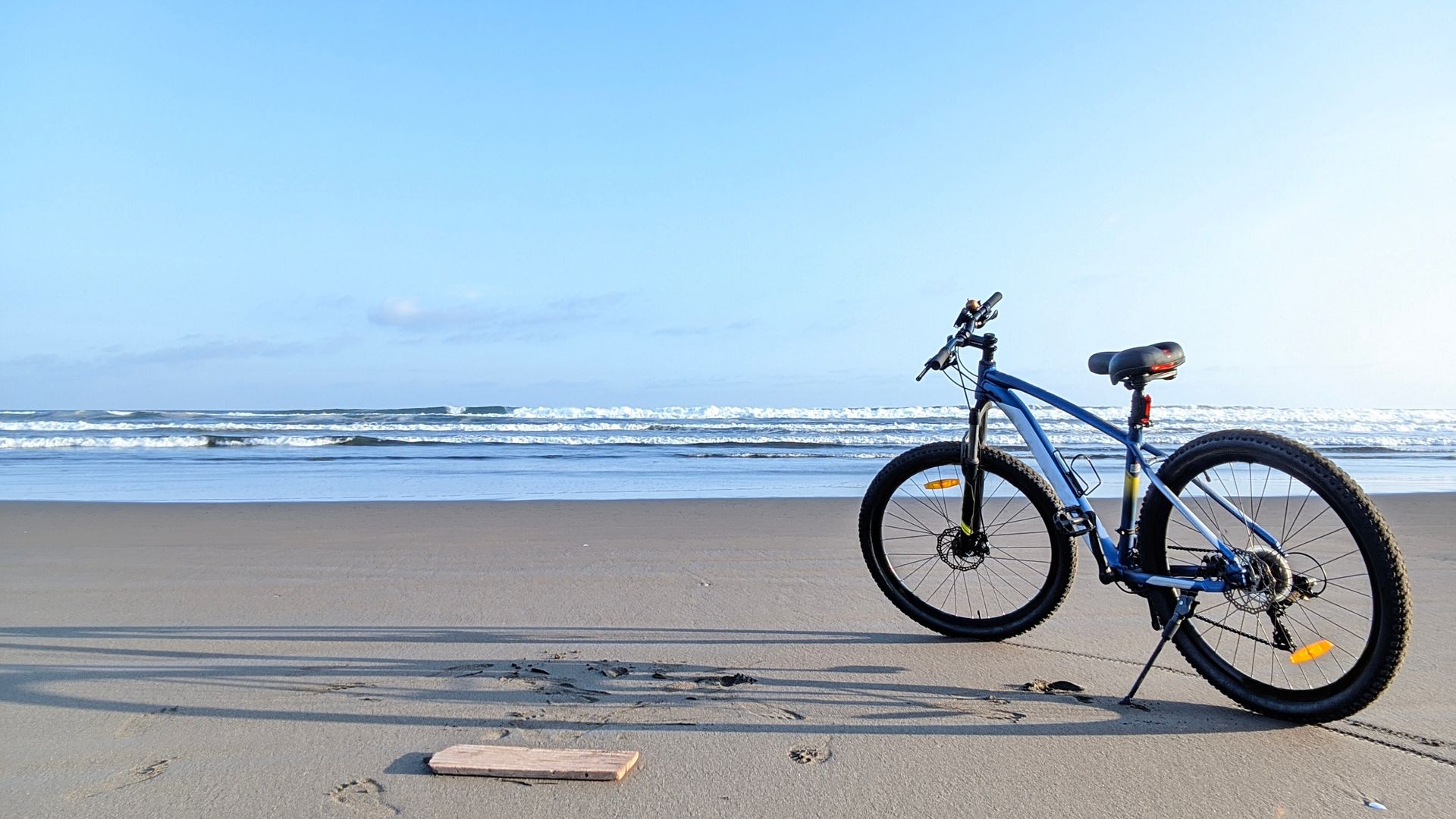 Black bicycle on a sandy beach with ocean waves in the background