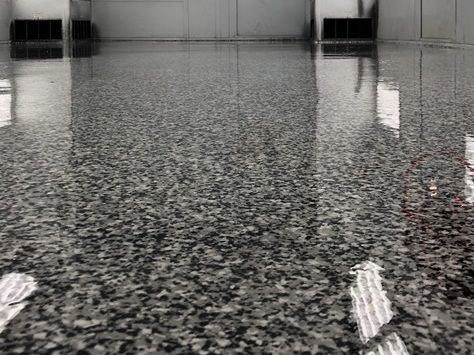 Empty glossy speckled floor with reflections in a bright indoor hallway