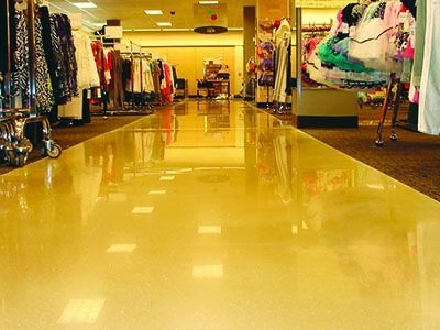 Empty clothing store with shiny yellow floor and racks of colorful clothes on both sides
