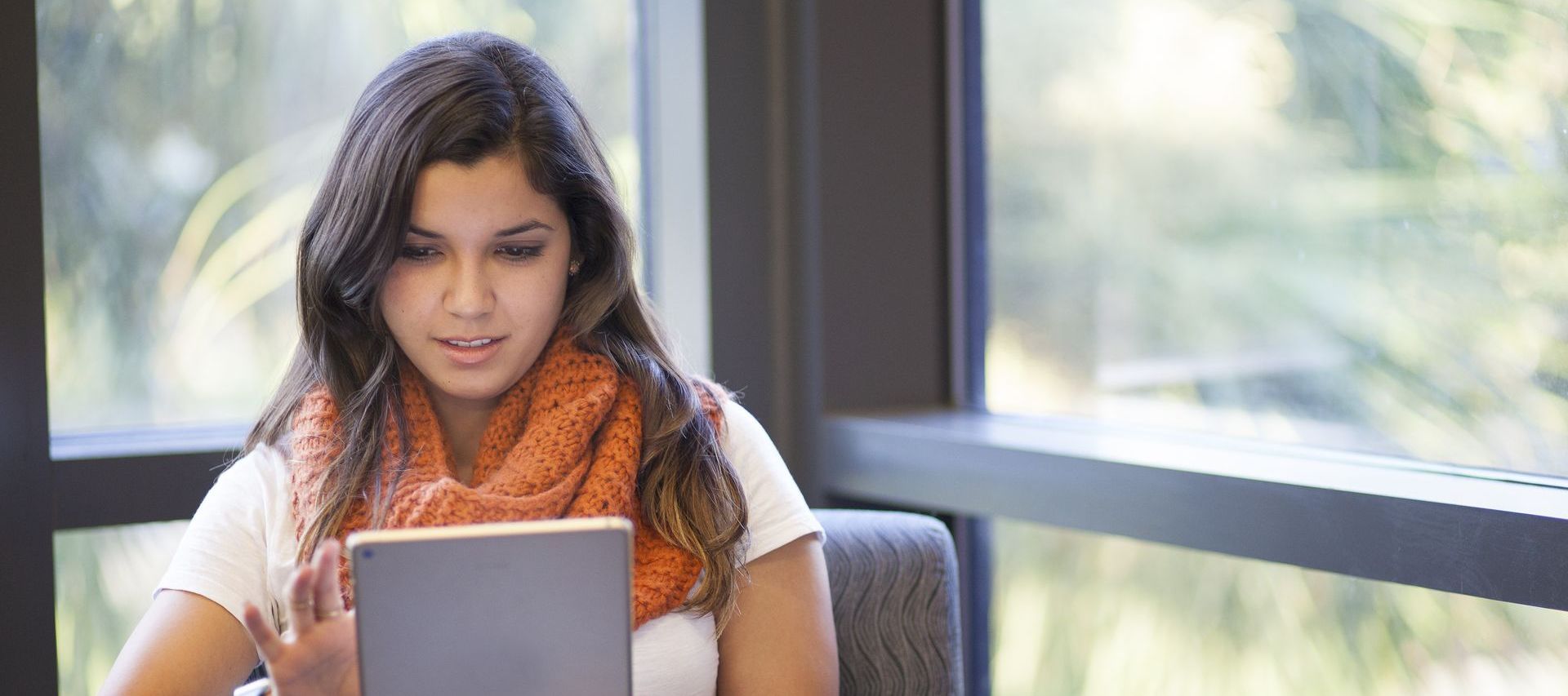 a woman wearing an orange scarf is using a tablet computer