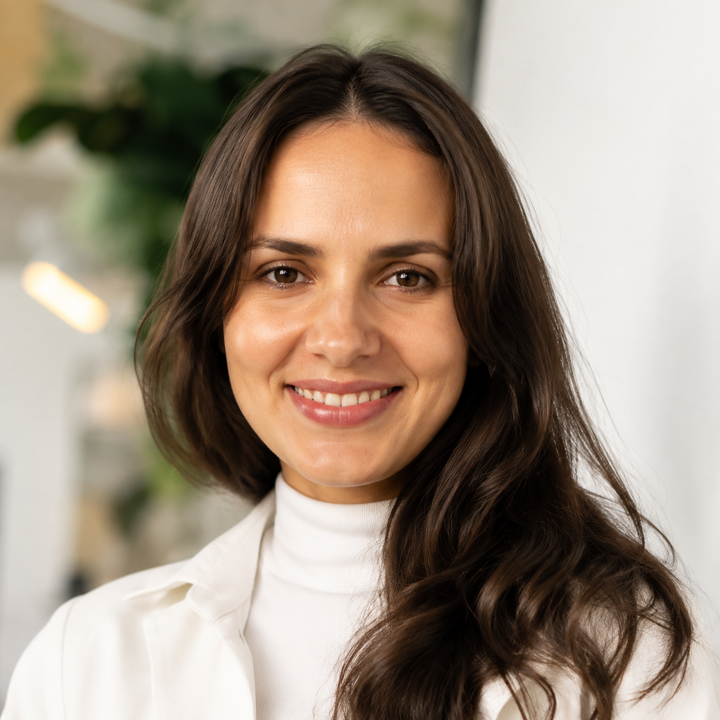Portrait of a smiling woman in a white blouse against a softly blurred indoor background