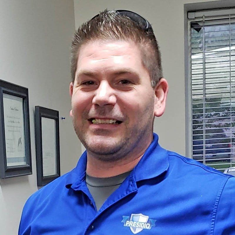 Smiling man in a blue collared shirt standing in an office