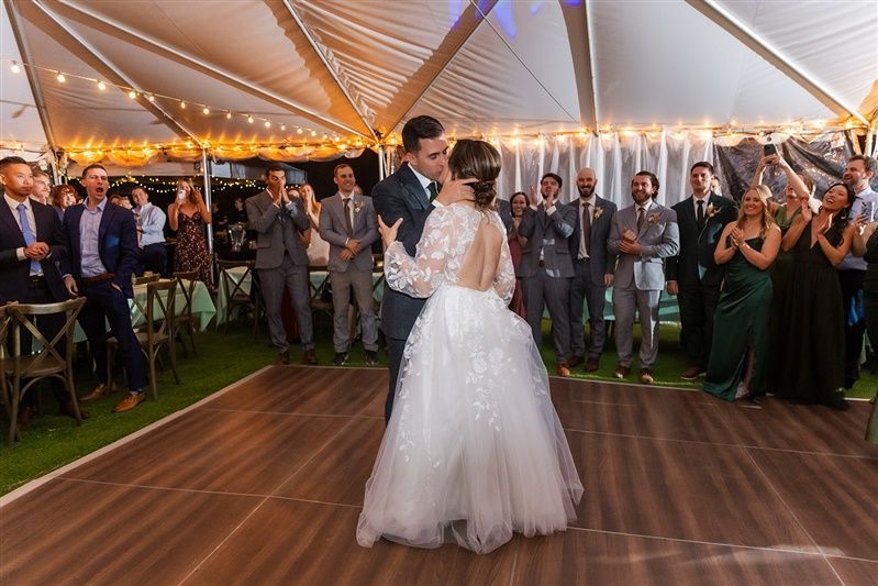 A bride and groom are dancing under a tent at their wedding reception.