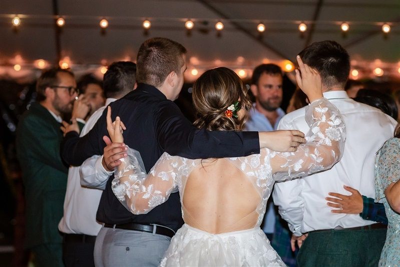 A bride and groom are dancing with their guests at a wedding reception.