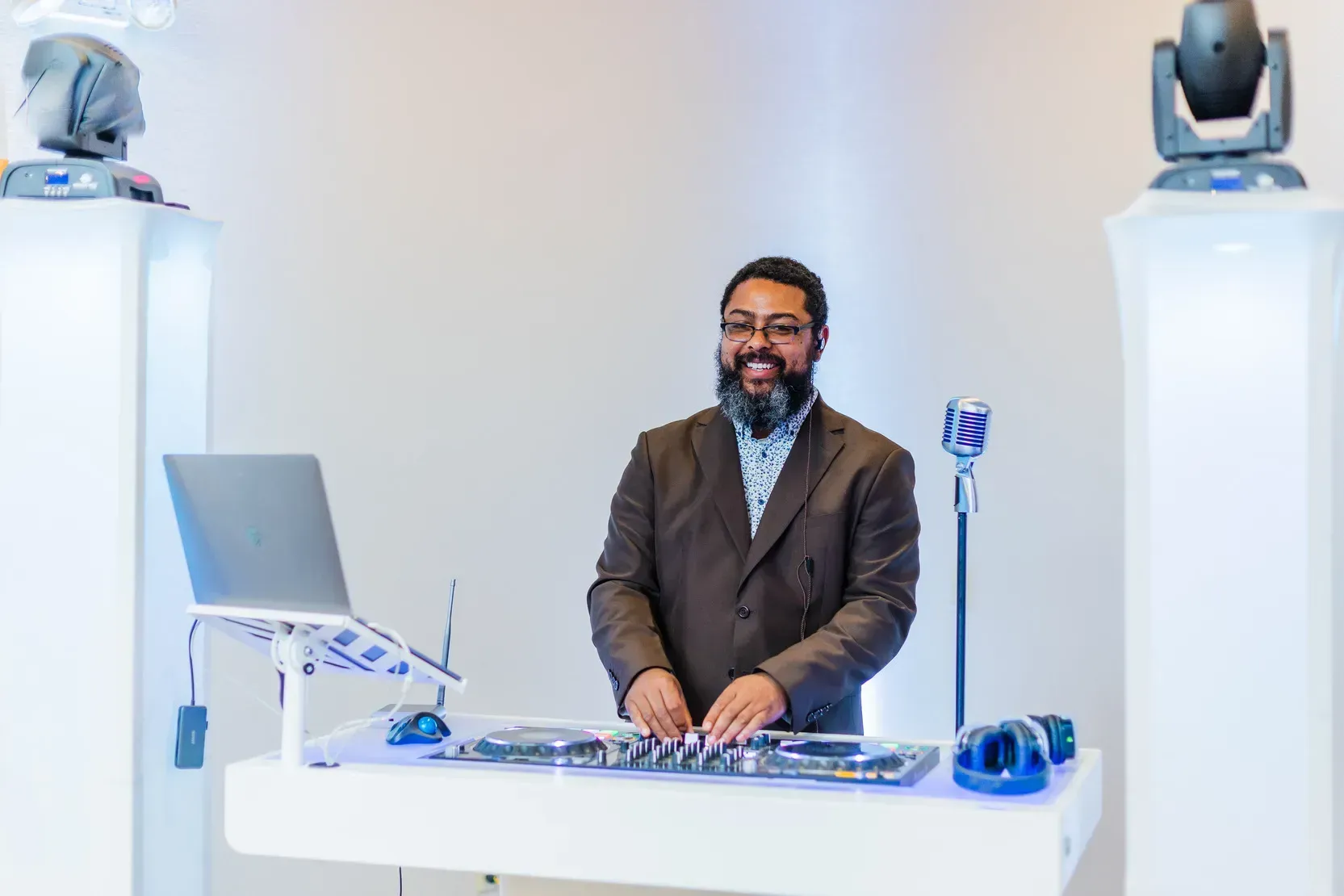 A man in a suit is standing in front of a dj booth.