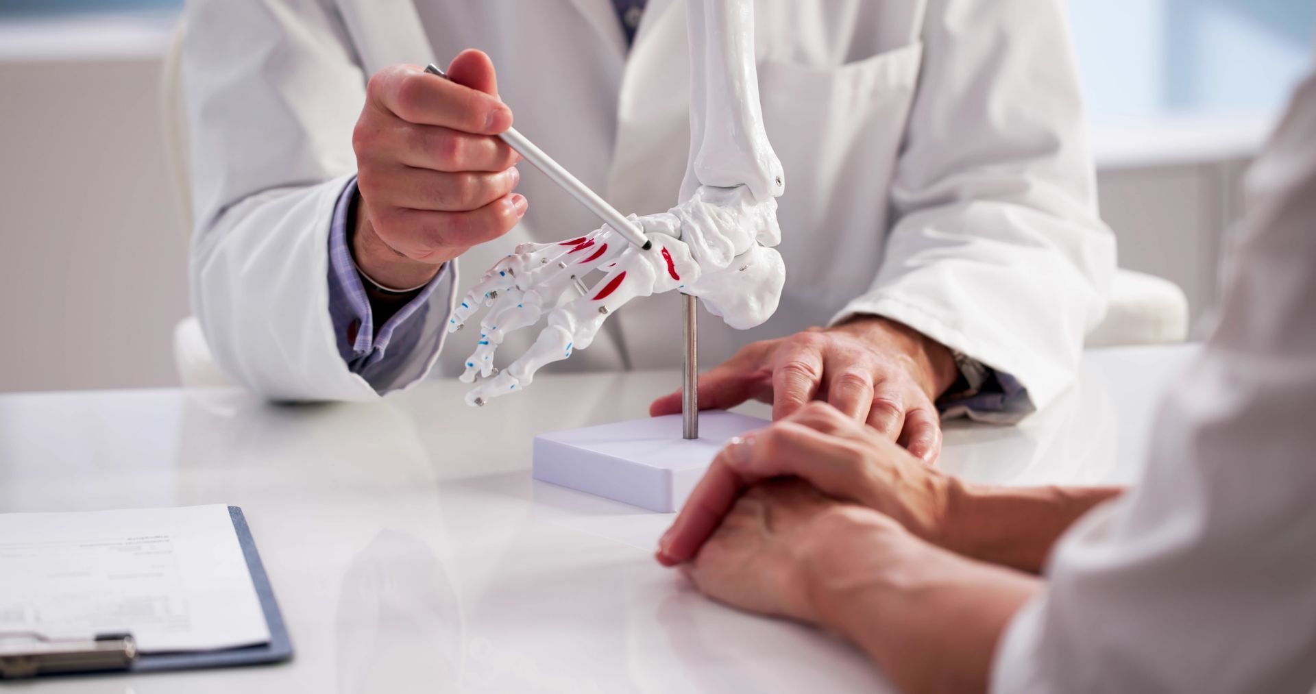 Podiatrist explaining foot structure using a model while consulting with a patient. Podiatrist explaining foot structure using a model while consulting with a patient.