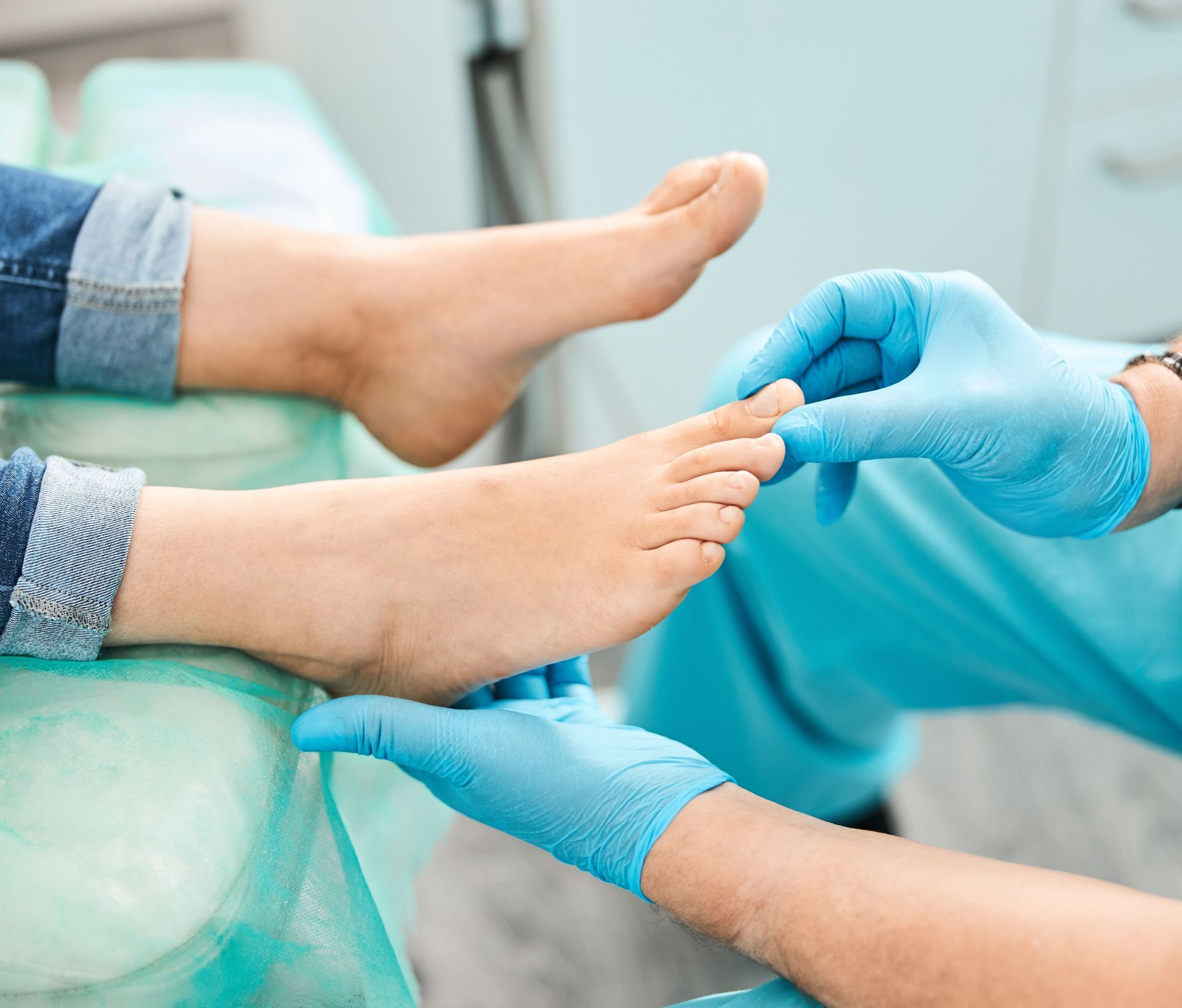 Doctor hands in blue gloves checking patient foot and ankle during orthopedic medical exam.