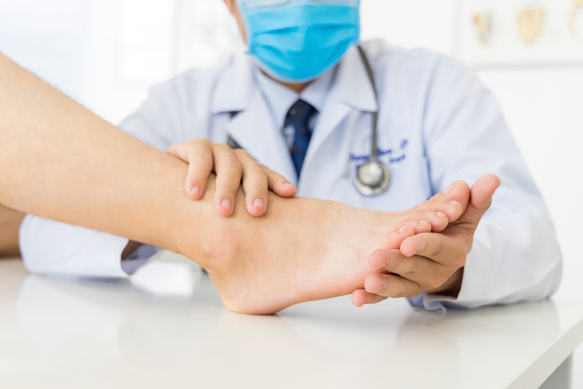 Doctor examining patient ankle during medical consultation in clinic.
