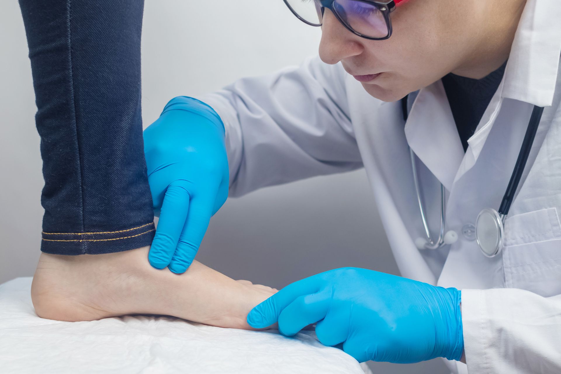 Doctor examines foot while wearing gloves and stethoscope.