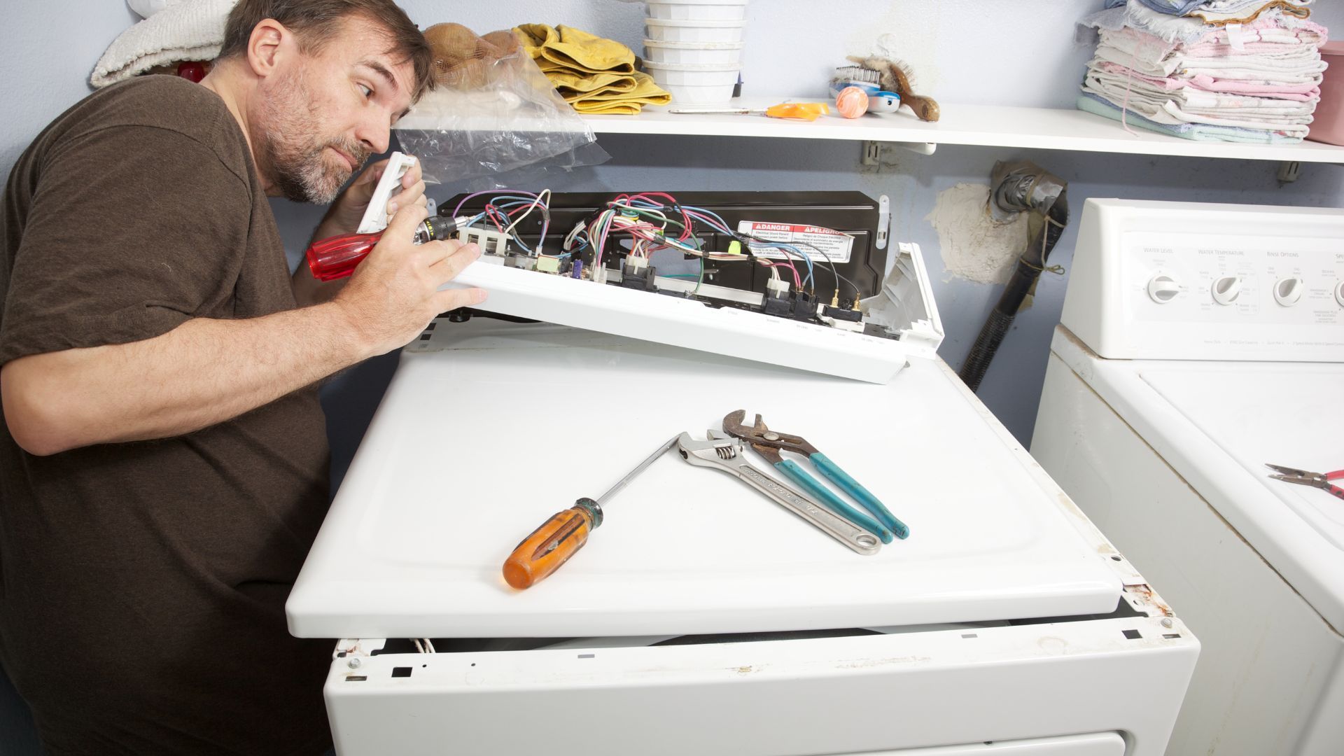 A man is working on a washer and dryer in a laundry room