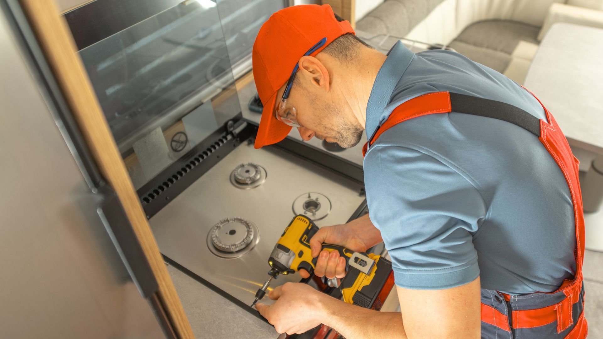 A man is working on a stove top oven in a kitchen.