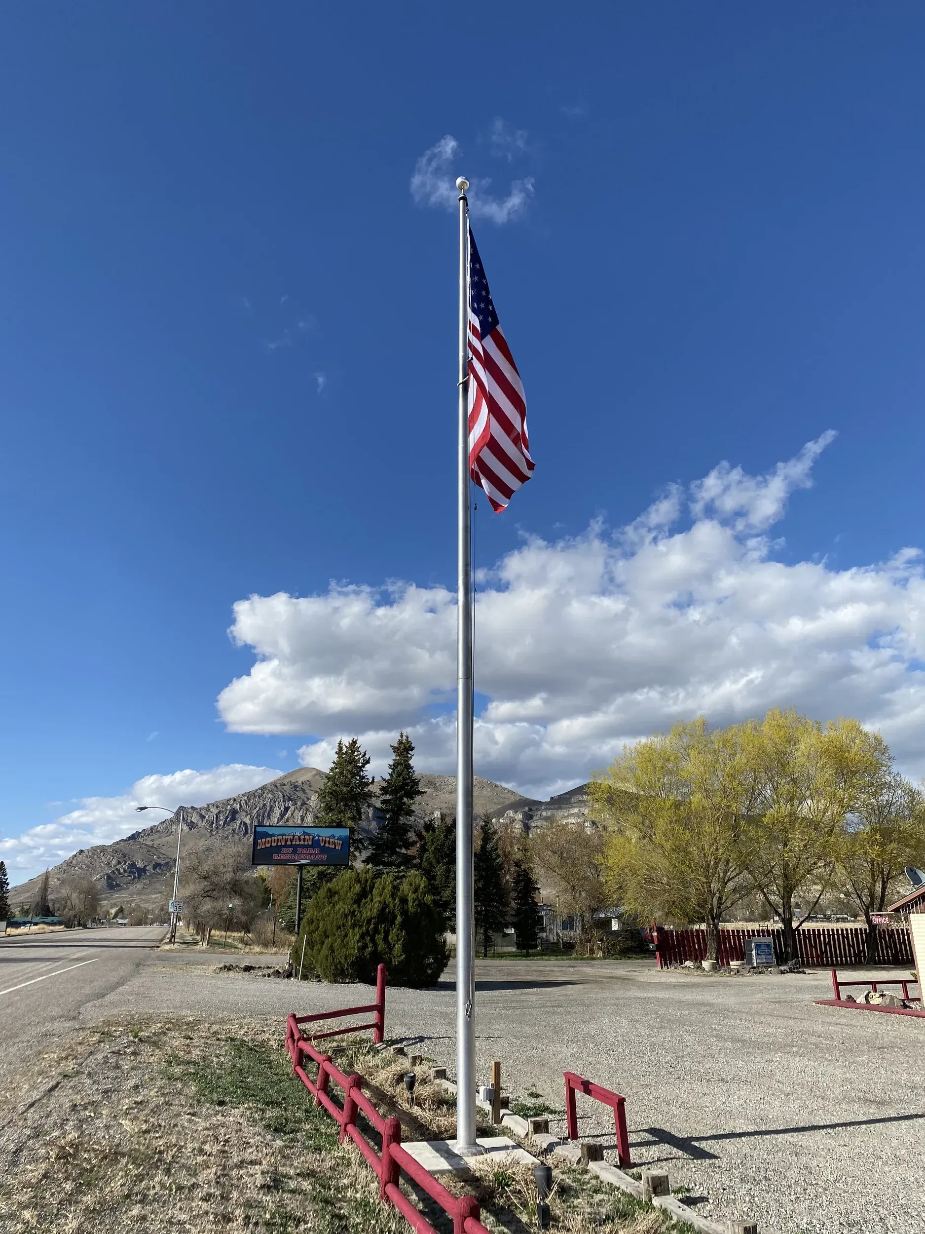 American flag waving on a tall flagpole under a partly cloudy blue sky.