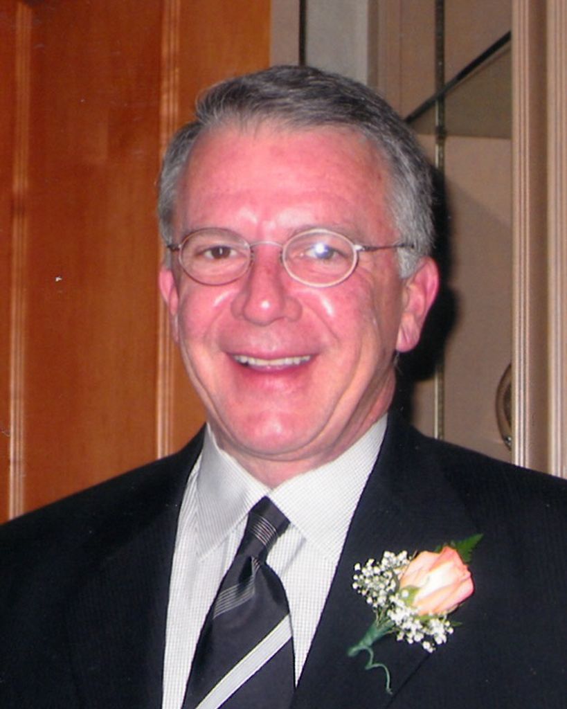 Man in suit and tie with brown hair, looking at the camera. Studio setting, striped tie.