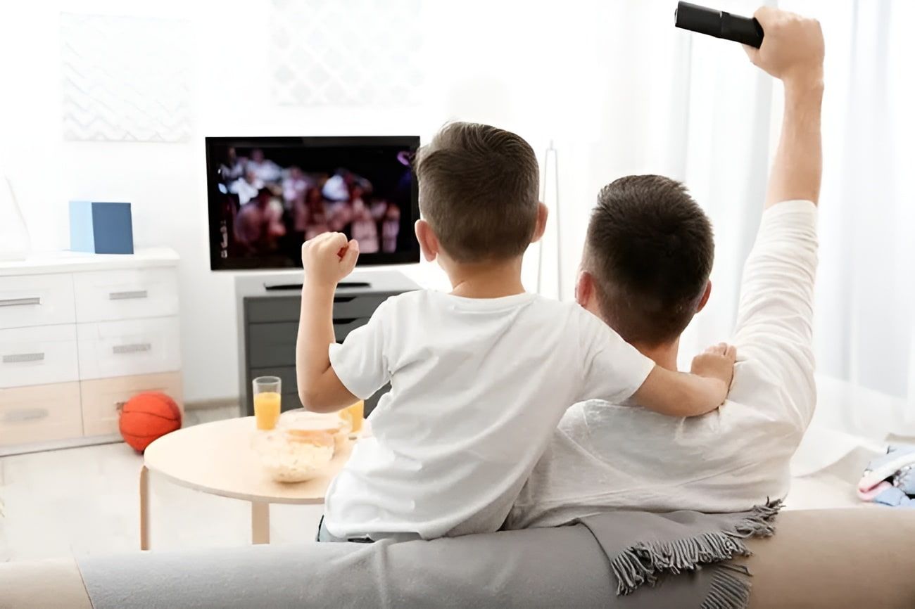 A Man and a Boy Are Sitting on a Couch Watching a Television — Garrow's TV & Antenna Services in Sunshine Coast, QLD