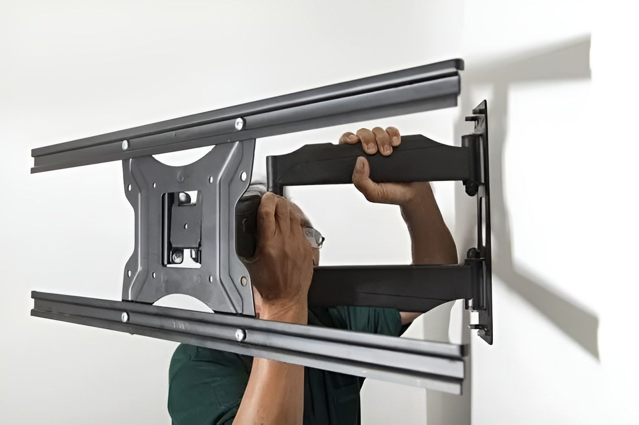 A Man is Installing a Tv Mount on a Wall — Garrow's TV & Antenna Services in Caloundra, QLD