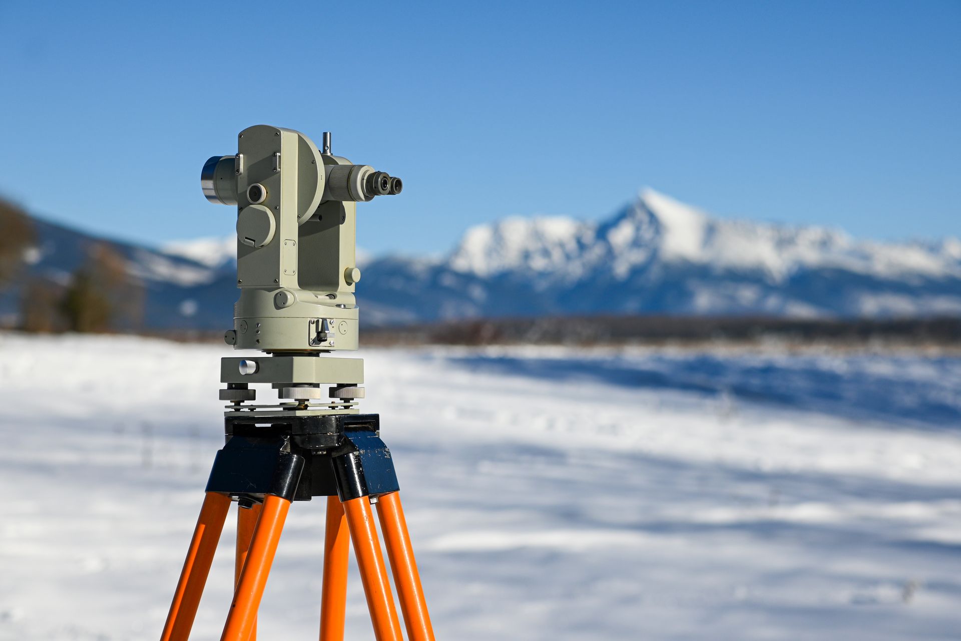 Surveying equipment set up in a winter mountainous landscape.