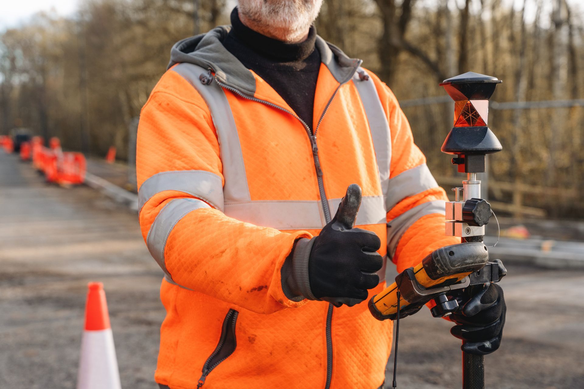 A close-up of a surveyor working with equipment at a construction site.