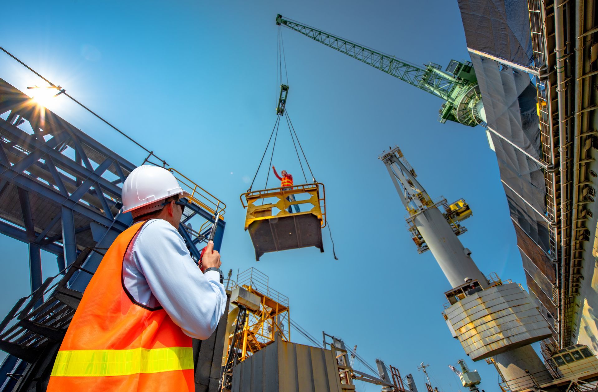 An engineer operating a crane at a building site, focused on lifting materials.