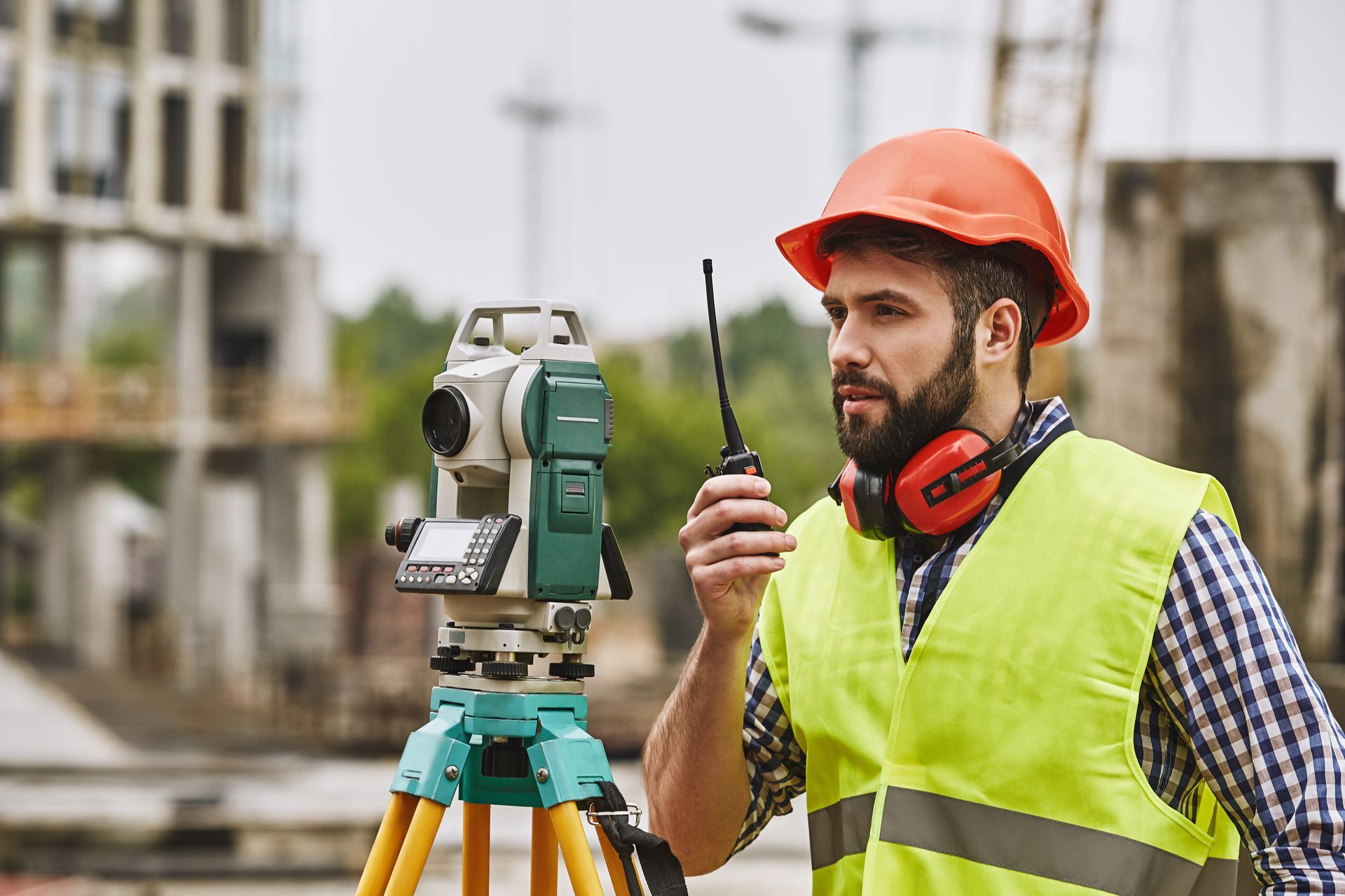 Land Surveying professional using a total station and radio at an active construction site.