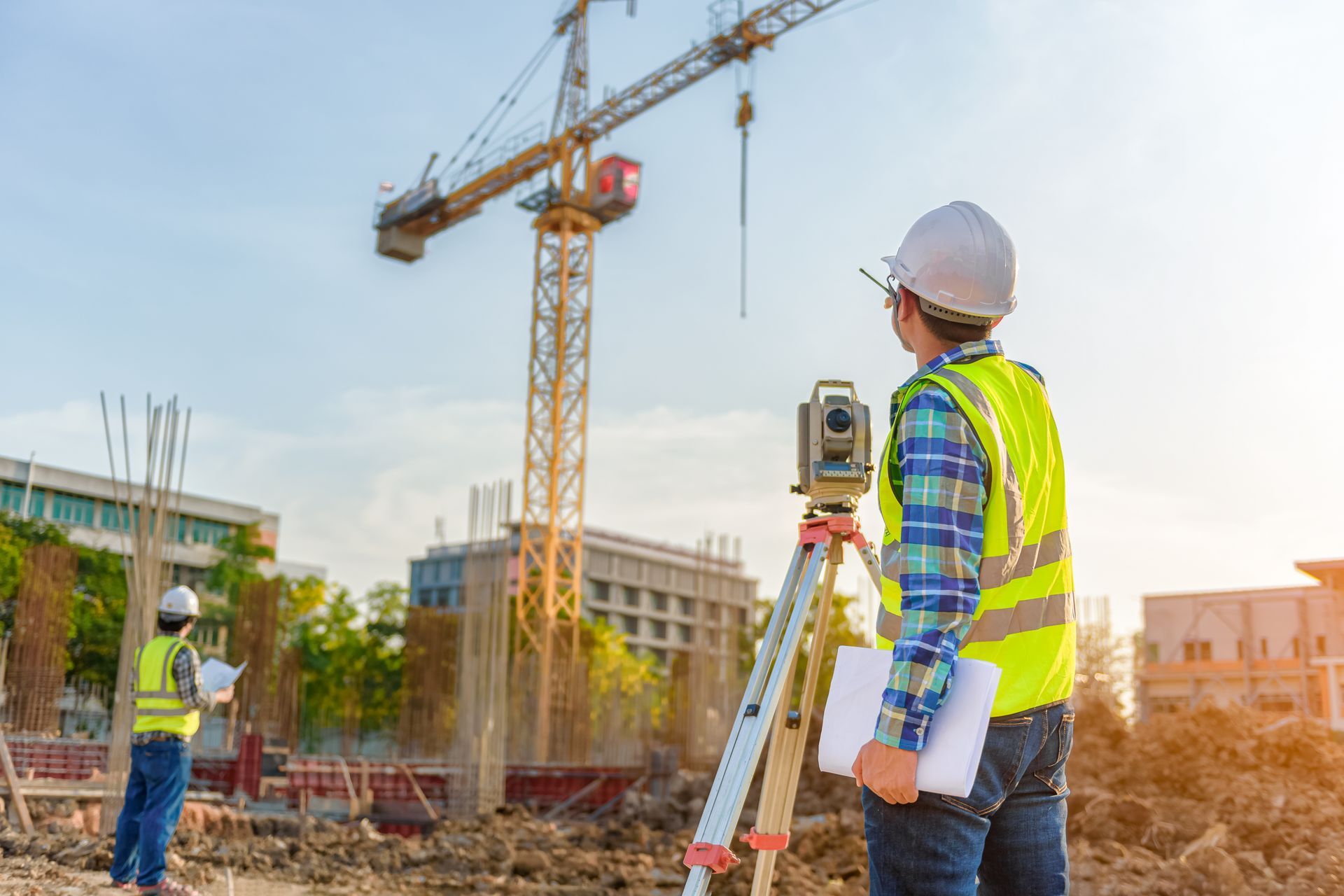 Surveying engineers are working together using a theodolite on the construction site.