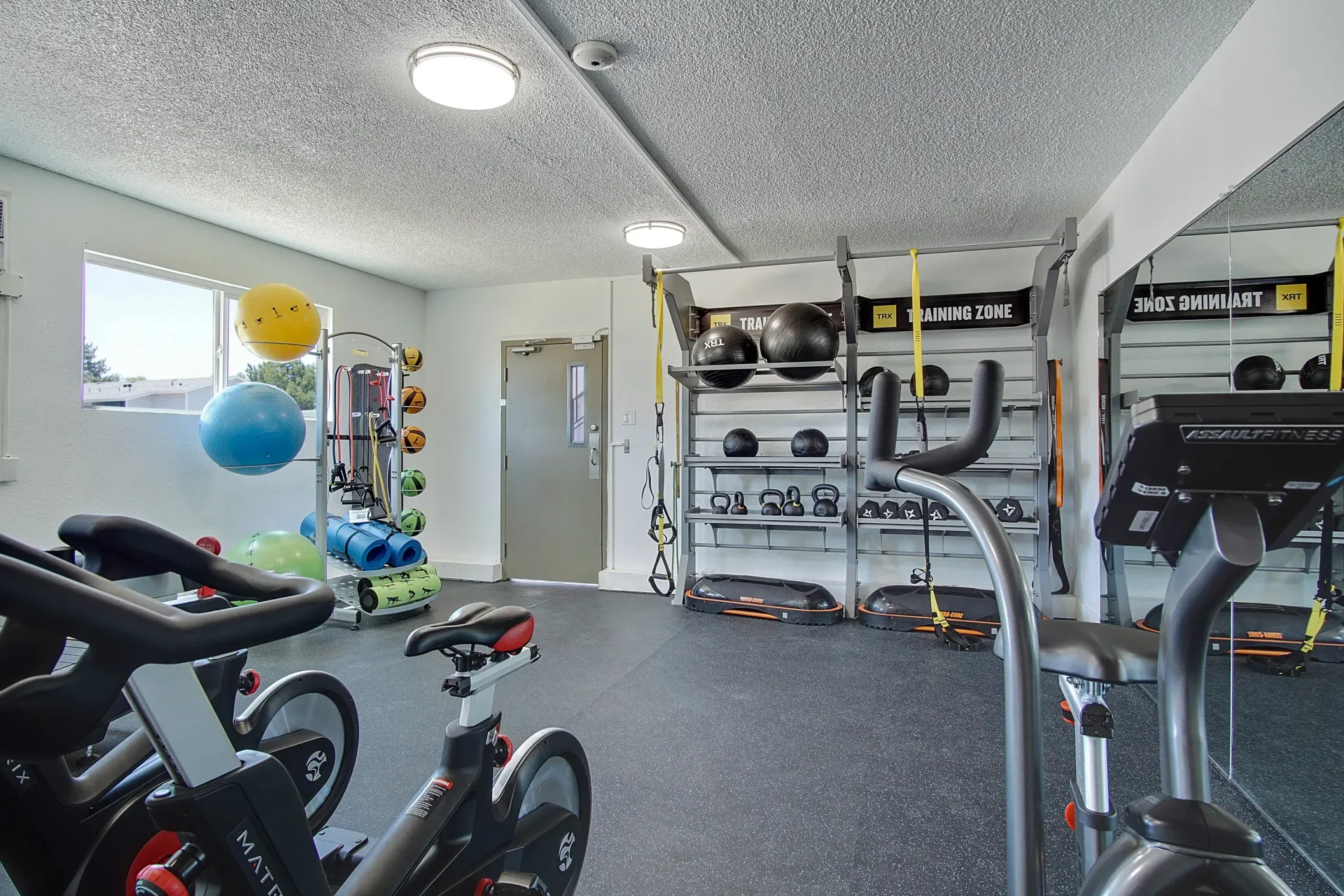 Indoor resident gym with stationary bikes, medicine balls, kettlebells, and mirrors at Marina's Edge.
