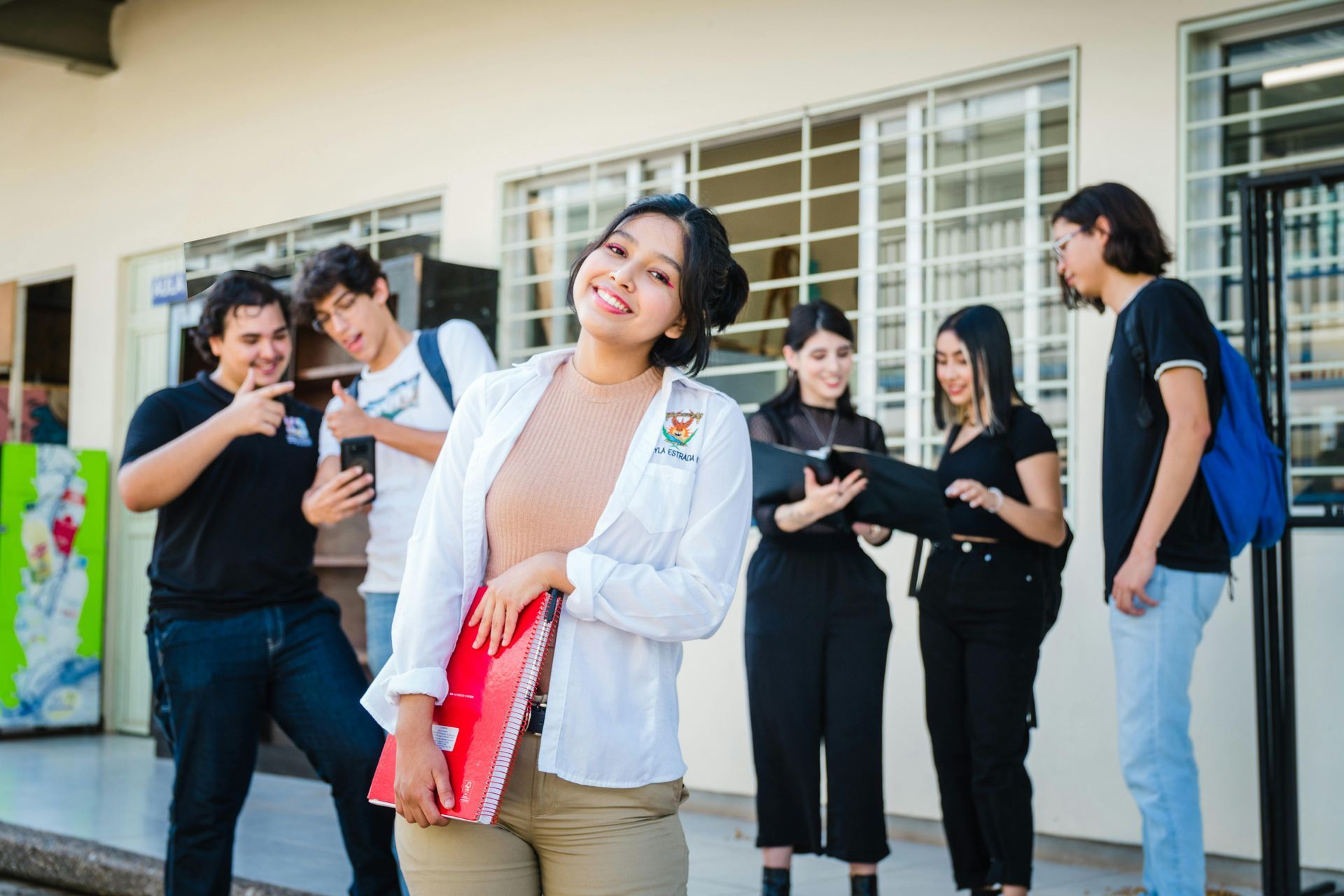 Un grupo de personas charlando frente a un edificio; una de ellas, con una chaqueta blanca