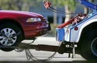 Picture of Red Car being towed down the street by tow truck