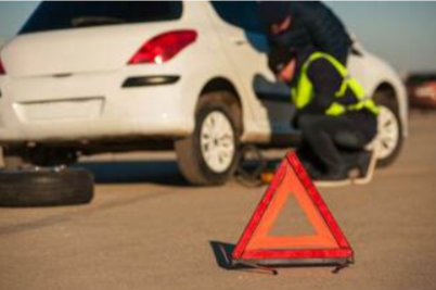 Picture of White Car on side of the road getting tire changed