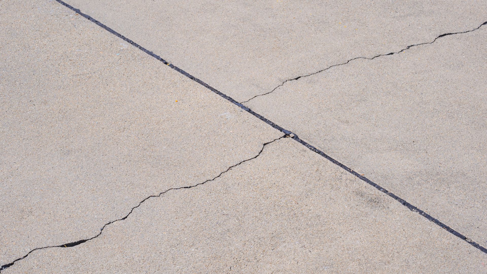A close up of a cracked concrete surface with a black line.