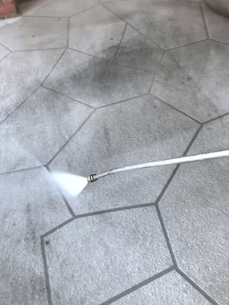 A clean water jet cuts through grime on the surface of hex tiles. A clean water jet cuts through grime on the surface of hex tiles.