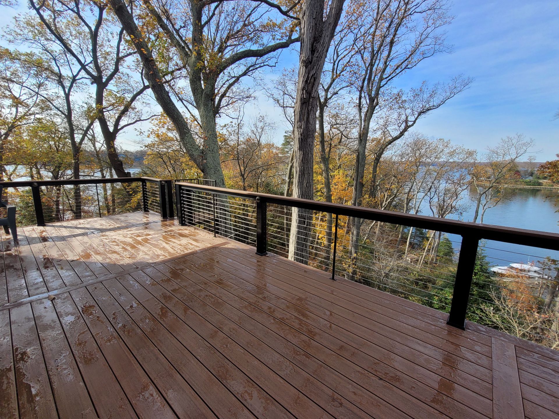 Wooden deck overlooking a lake and autumn trees under a clear blue sky
