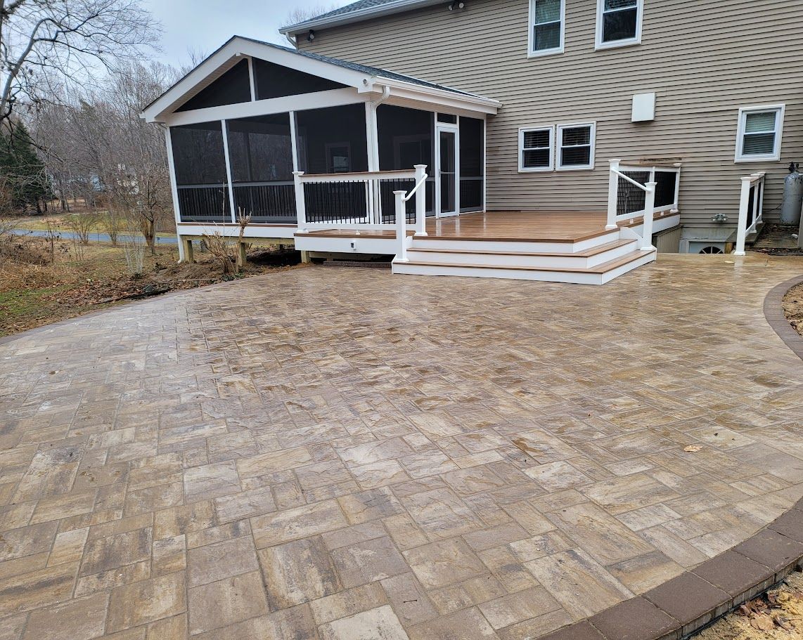A screened in porch with a deck and a patio in front of a house.